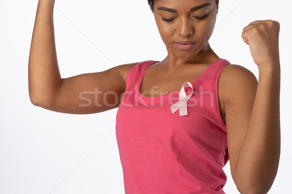 Woman putting up fists and looks at pink ribbon for breast cancer awareness Stock photo © wavebreak_media