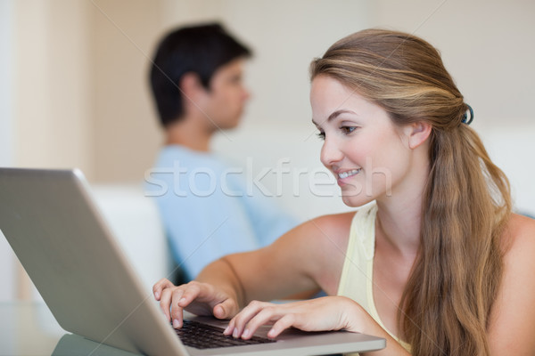 Woman using a laptop while her fiance is sitting on a sofa in their living room Stock photo © wavebreak_media