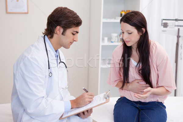 Stock photo: Young male doctor writing down patients symptoms