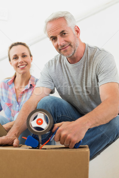 Stock photo: Happy couple sealing cardboard moving boxes