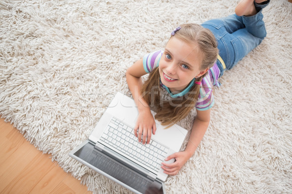 Cute girl using laptop while lying on rug Stock photo © wavebreak_media