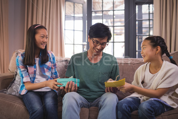 Father receiving greeting card and gift box from siblings in living room Stock photo © wavebreak_media