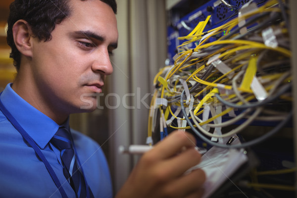 Technician maintaining record of rack mounted server on clipboard Stock photo © wavebreak_media