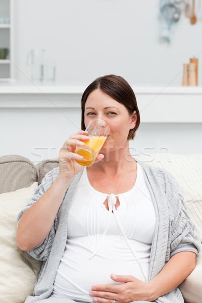 Pregnant woman drinking oranje juice on her sofa Stock photo © wavebreak_media