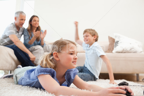 Cute children playing video games with their parents on the background in the living room Stock photo © wavebreak_media