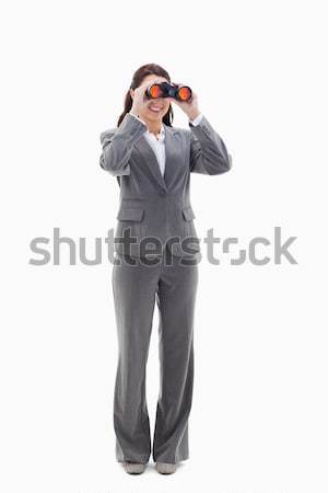 Businesswoman smiling and looking through binoculars on the left side against white background Stock photo © wavebreak_media