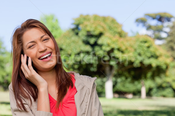 Young woman laughing joyfully while on the phone in a bright grassland  area Stock photo © wavebreak_media