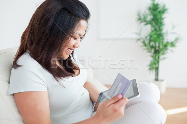 Woman on a couch while holding a tactile tablet and a card in a living room Stock photo © wavebreak_media