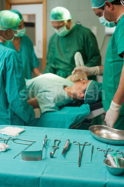 Stock photo: Surgery trolley with surgical tools in front of a medical team in a surgical room