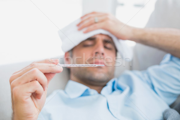 Sick man lying on sofa checking his temperature Stock photo © wavebreak_media