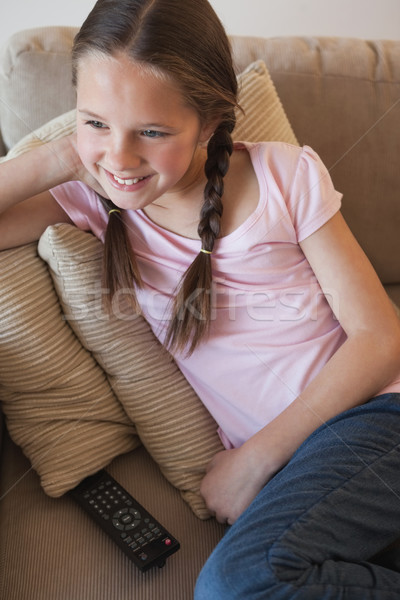 Smiling girl sitting on sofa in the living room Stock photo © wavebreak_media