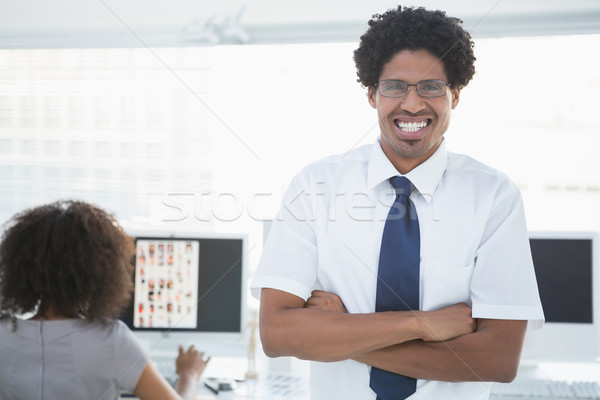 Young handsome editor smiling at camera with colleague working b Stock photo © wavebreak_media