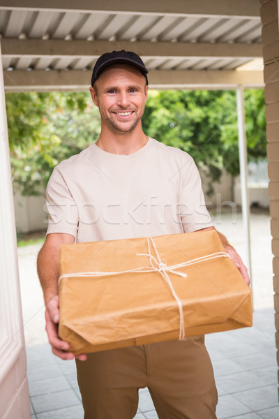 Foto stock: Mensajero · sonriendo · cámara · ofrecimiento · paquete · fuera