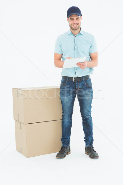 Stock photo: Happy delivery man writing on clipboard