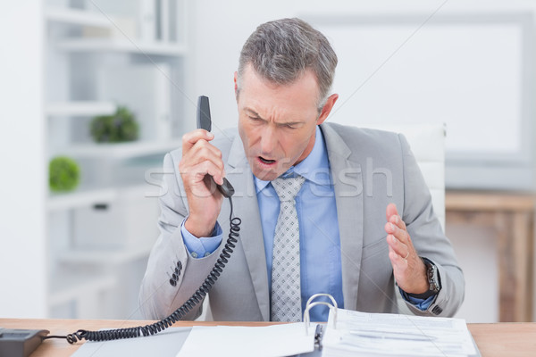 Stock photo: Irritated businessman answering phone 