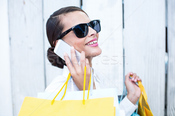 Stock fotó: Csinos · nő · telefon · tart · bevásárlótáskák · fából · készült · szürke
