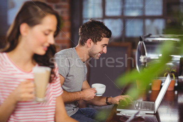 Stock photo: Smiling young man sitting at bar and using laptop 