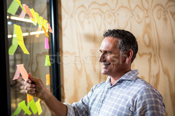 Man looking at sticky notes on window Stock photo © wavebreak_media