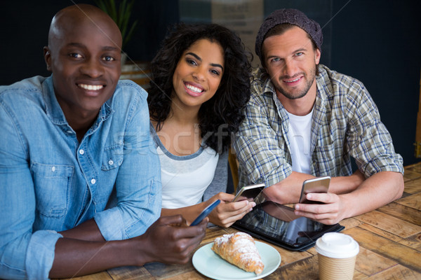 Glimlachend vrienden smart telefoons tabel Stockfoto © wavebreak_media