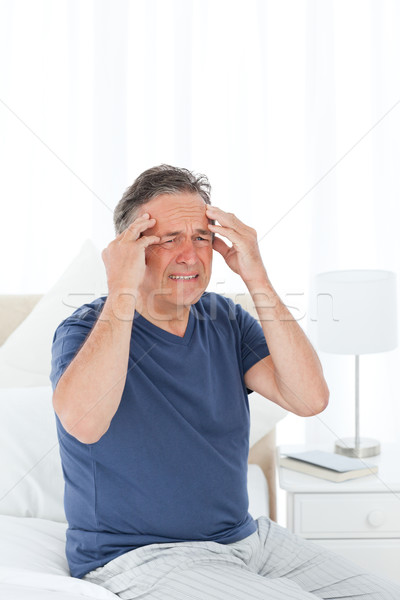 Man having a headache on his bed Stock photo © wavebreak_media