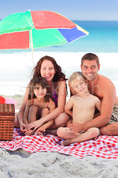 Stock photo: Family picnicking under a sol umbrella on the beach