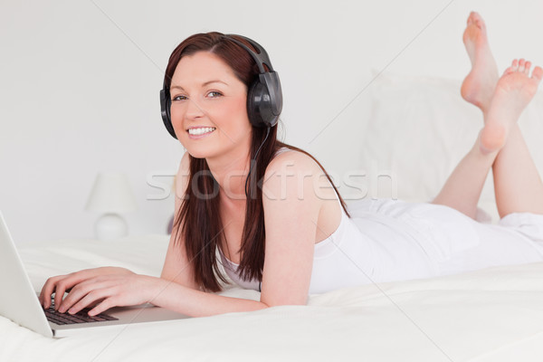Gyönyörű női megnyugtató laptop fejhallgató ágy Stock fotó © wavebreak_media