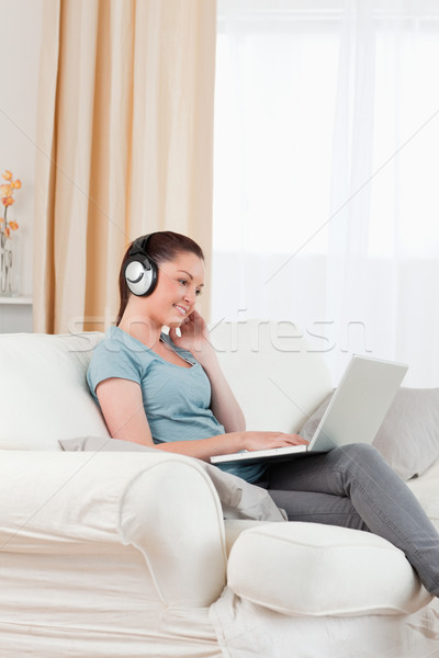 Piękna kobieta słuchawki relaks laptop posiedzenia sofa Zdjęcia stock © wavebreak_media