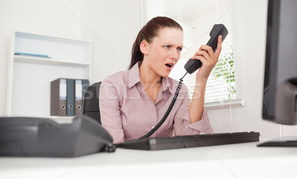 A depressed businesswoman shouting at telephone in her office Stock photo © wavebreak_media