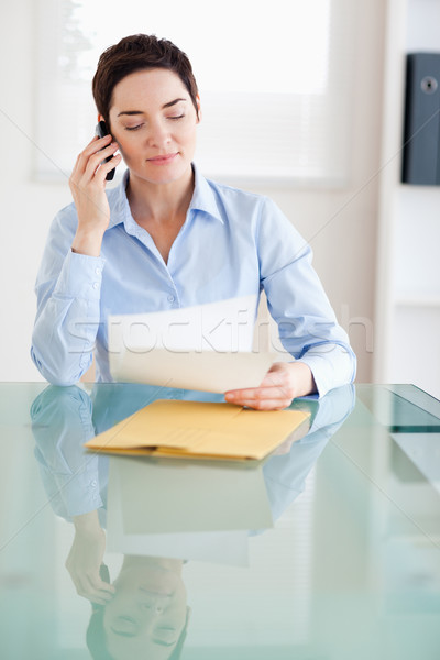 Businesswoman sitting behind a desk with papers on the phone in an office Stock photo © wavebreak_media