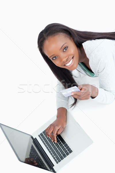 Stock photo: Smiling woman entering credit card information against a white background