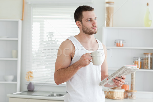 Dreaming man drinking coffee while reading the news in his kitchen Stock photo © wavebreak_media