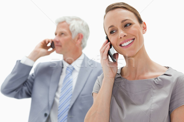 Close-up of a smiling woman making a call with a white hair businessman in background against white  Stock photo © wavebreak_media