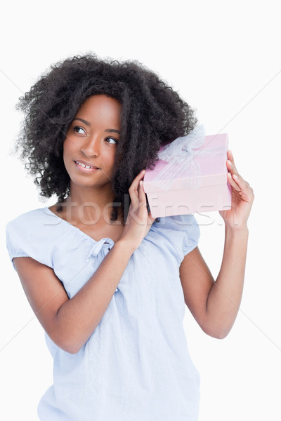 Young woman looking on the side while shaking a gift against a white background Stock photo © wavebreak_media