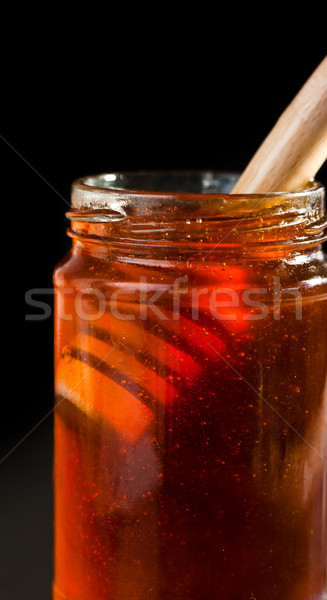 Close up of a honey jar with a honey dipper against a black bakground Stock photo © wavebreak_media