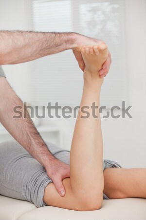 Stock photo: Physiotherapist bending the leg of a patient in a room