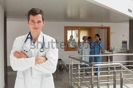 Stock photo: Laughing doctor standing in the hallway while crossing his arms