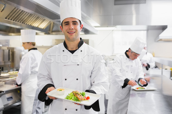 Happy chef holding salmon dish in kitchen Stock photo © wavebreak_media