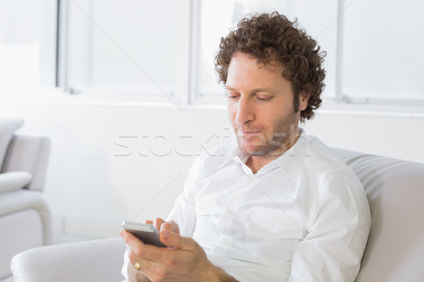 Nyugodt férfi sms üzenetküldés otthon fiatalember kanapé Stock fotó © wavebreak_media