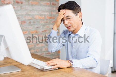 Tired businessman using computer at desk Stock photo © wavebreak_media