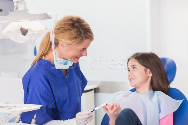 Stock photo: Smiling dentist teaching to her young patient how use toothbrush