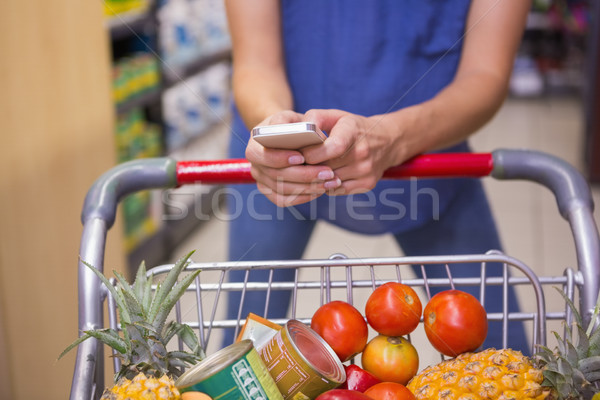 Woman pushing trolley in aisle and texting  Stock photo © wavebreak_media