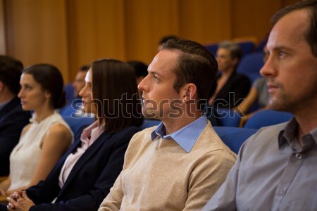 Female teacher looking at students talking while sitting on chair Stock photo © wavebreak_media
