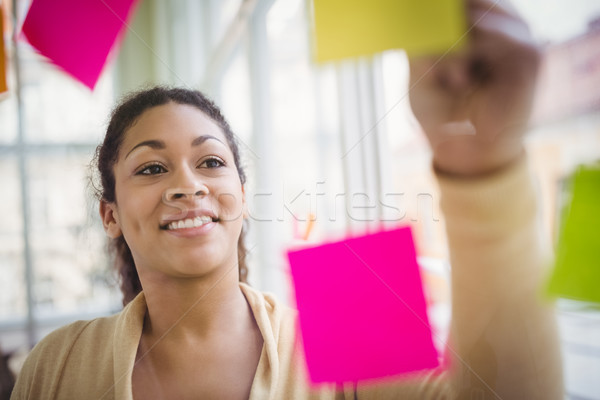 Young businesswoman smiling while writing on adhesive notes Stock photo © wavebreak_media