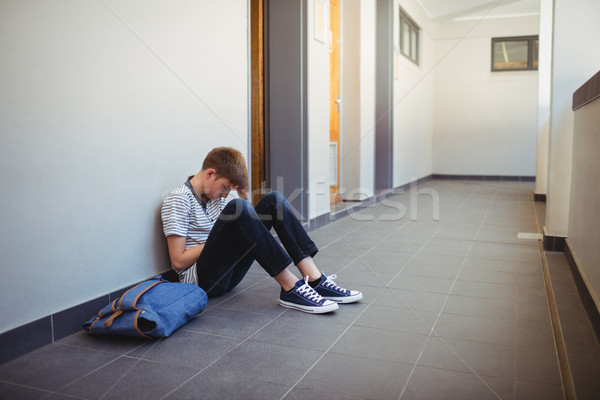 Sad schoolboy sitting in corridor Stock photo © wavebreak_media