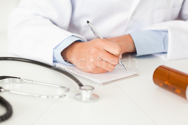 Young female doctor writing on a scratchpad in her office Stock photo © wavebreak_media