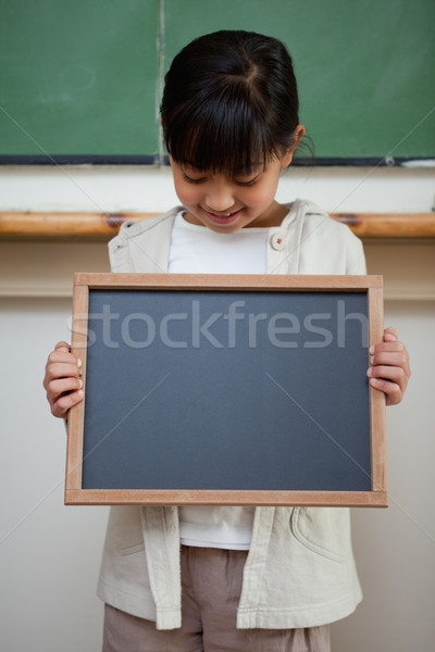 Portrait of a cute girl holding a school slate in a classroom Stock photo © wavebreak_media