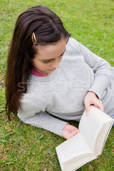 Young serious woman reading a book while lying down in a public garden Stock photo © wavebreak_media