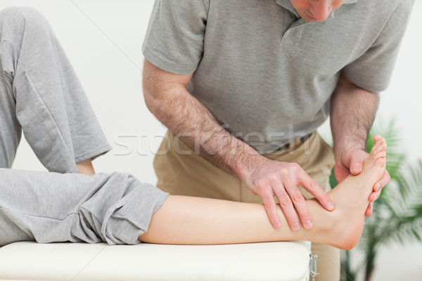 Doctor examining the foot of a woman in a room Stock photo © wavebreak_media