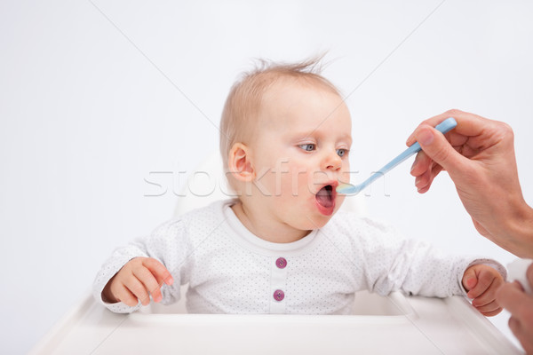 Baby being fed by her mother against a grey background Stock photo © wavebreak_media