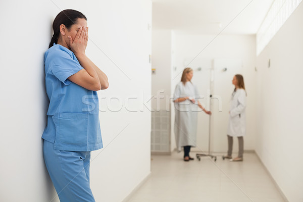 Nurse leaning against wall with head in hands in hospital corridor Stock photo © wavebreak_media